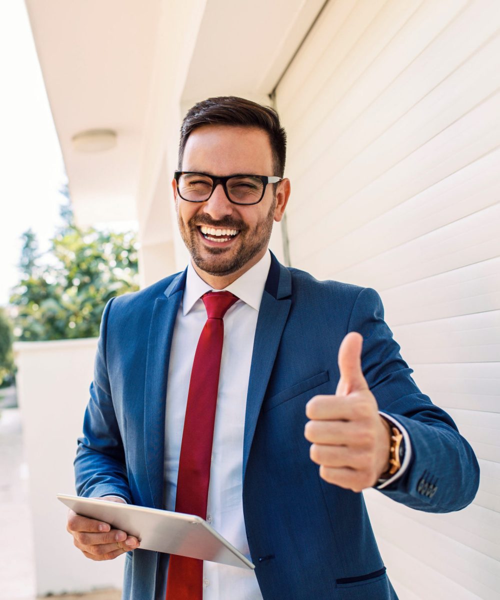 Handsome young smiling salesman giving thumbs up